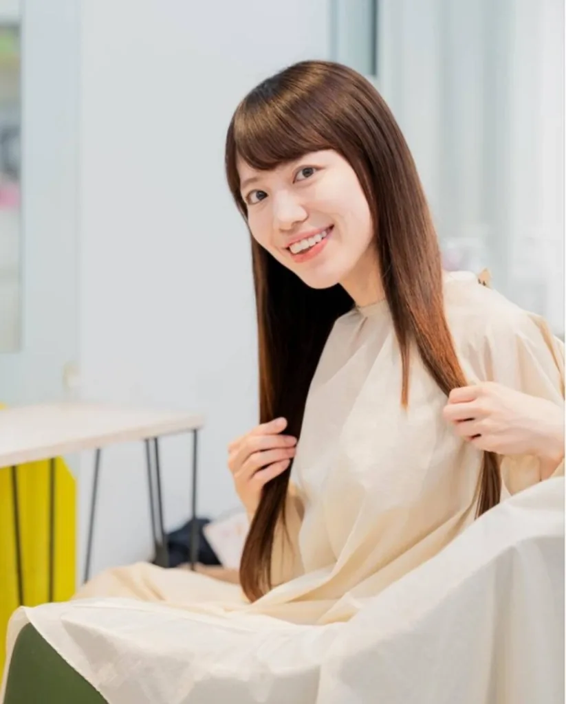 施術ケープ姿でロングヘアを見せるお客様